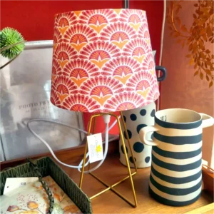 Eine Tischlampe von Clayre und Eef mit einem rosa-orange ornametierten Schirm. Ein einfacher, stylischer Fuß aus golden beschichtetem Metallrohr.