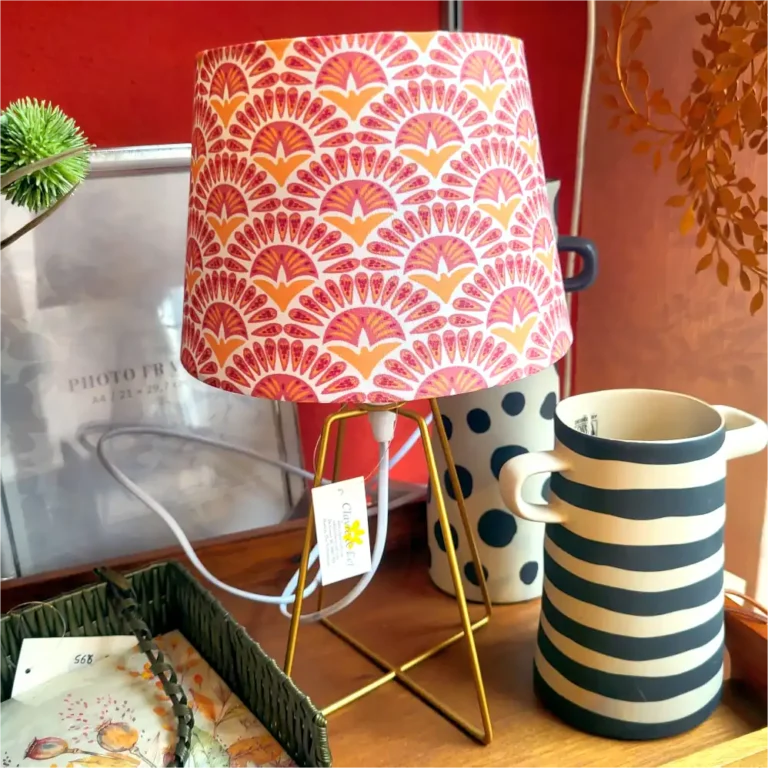 Eine Tischlampe von Clayre und Eef mit einem rosa-orange ornametierten Schirm. Ein einfacher, stylischer Fuß aus golden beschichtetem Metallrohr.